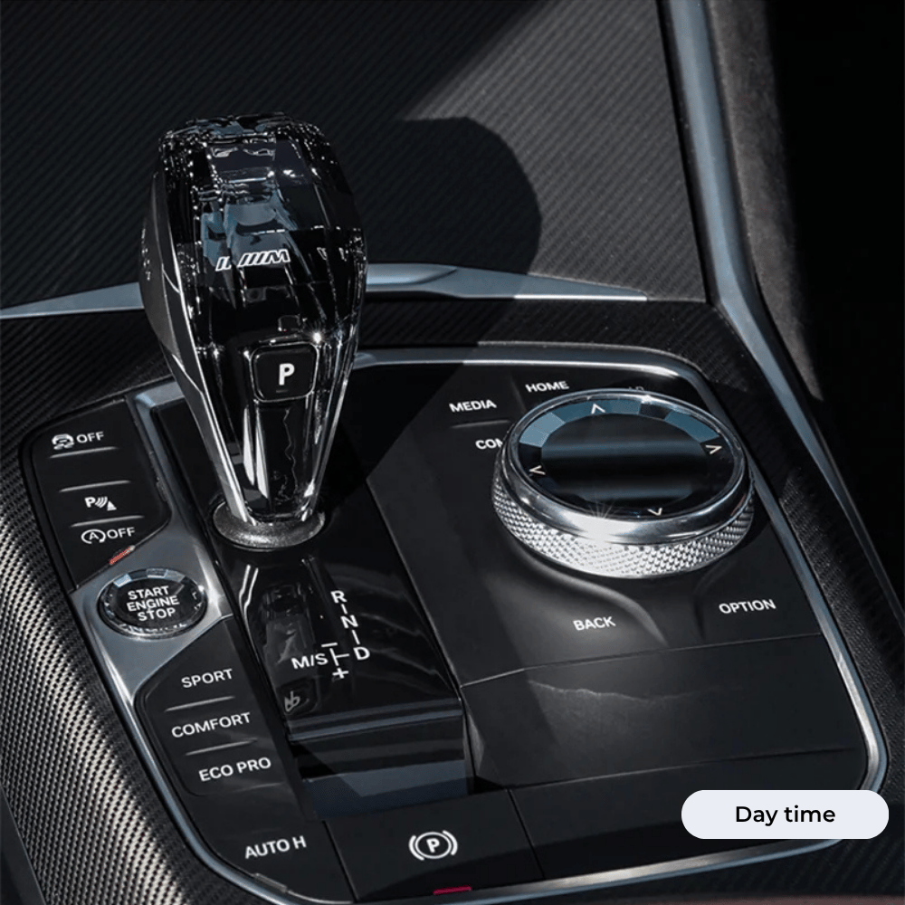 A close-up view of a modern car’s center console featuring a crystal gear shifter, rotary control dial, and various driving mode buttons in day time.